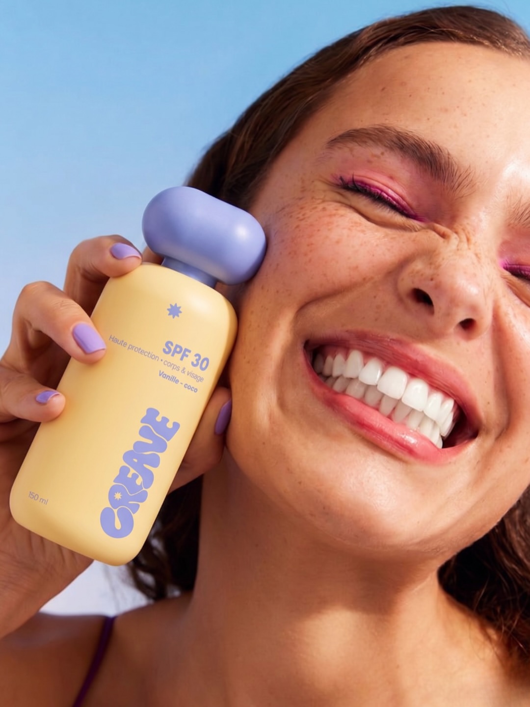 Portrait d'une femme posant le flacon CREAVE SPF 30 au capuchon lavande contre sa joue